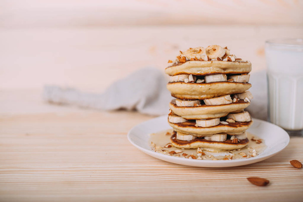 Stapel heerlijke pannenkoeken met honing, noten en plakjes banaan - Foto, afbeelding