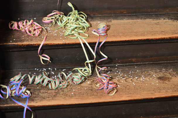 na een partij overgebleven kleurrijke confetti en papieren linten op houten treden - Foto, afbeelding