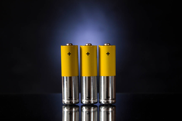 Tres baterías recargables de color naranja sobre un fondo azul retroiluminado
. - Foto, imagen