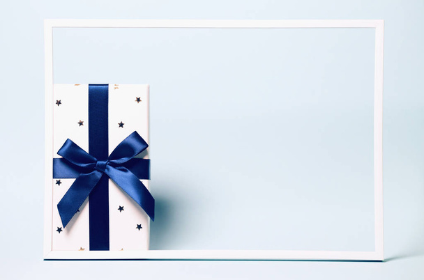 Настоящая коробка, завернутая голубой лентой на красочном фоне остроумия
 - Фото, изображение