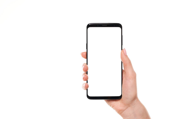 Woman hand holding the black smartphone blank screen with modern frameless design isolated on white background - Valokuva, kuva