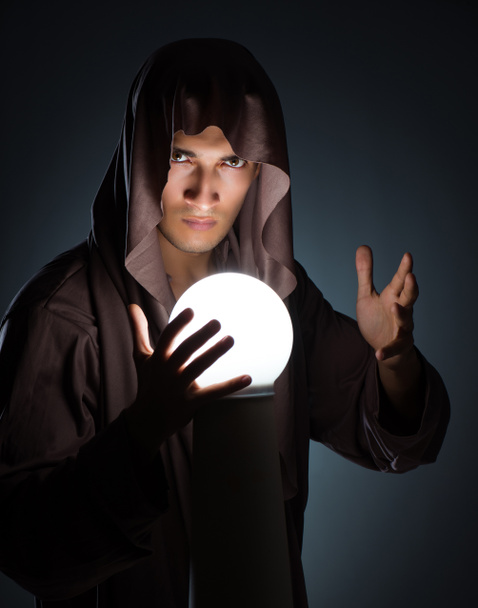 Young wizard with crystal ball in dark room - Photo, Image