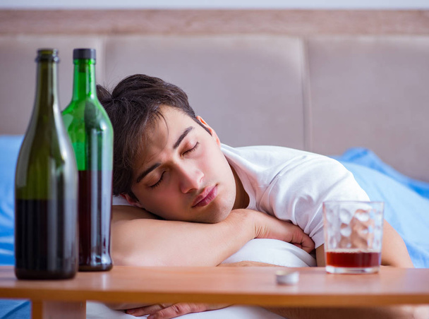 Hombre alcohólico bebiendo en la cama pasando por romper la depresión - Foto, Imagen