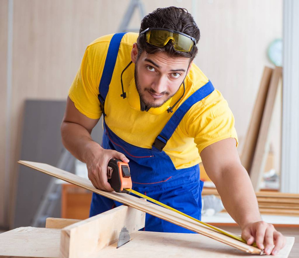 carpintero joven reparador que trabaja cortando madera en sierra circular - Foto, Imagen