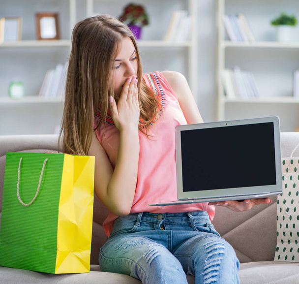 Young woman with shopping bags indoors home on sofa - Foto, imagen