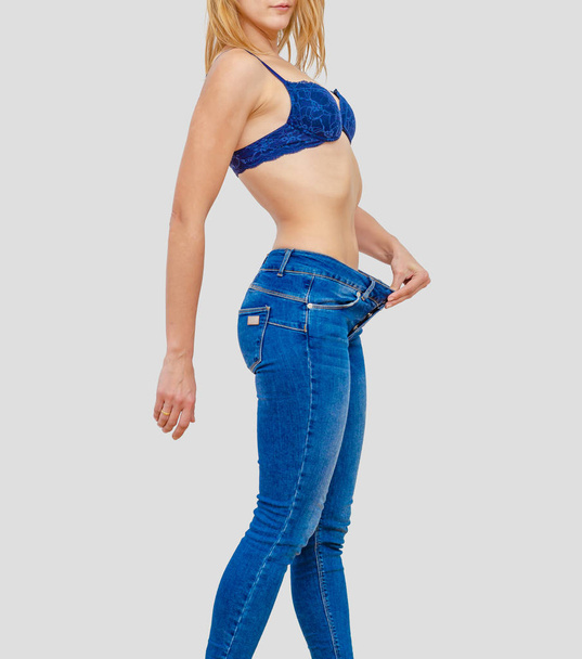 Femme montre la perte de poids en vieux gros jeans
 - Photo, image