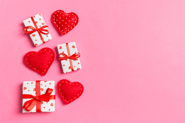 Composición festiva de cajas de regalo y corazones textiles rojos sobre fondo colorido con espacio vacío para su diseño. Vista superior del concepto de San Valentín - Foto, imagen