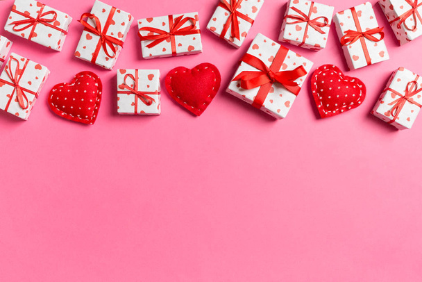 Bovenaanzicht van geschenkdozen en rode textielhartjes op kleurrijke achtergrond. Valentijnsdag concept met kopieerruimte - Foto, afbeelding
