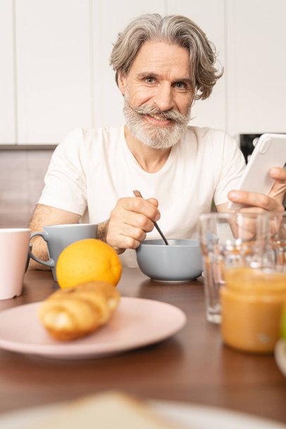 Mature man eating muesli in the morning - Foto, Imagem