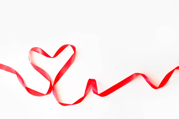 Corazón hecho de cinta de seda roja aislada sobre un fondo blanco. Concepto de San Valentín, 14 de febrero
 - Foto, imagen