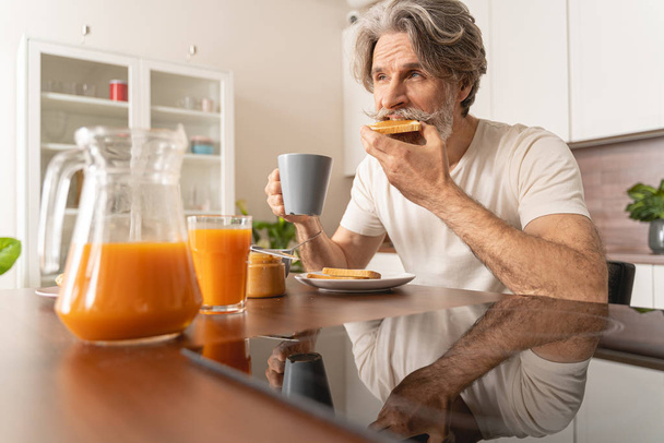 ernsthafter Mann isst seinen Erdnussbutter-Toast - Foto, Bild