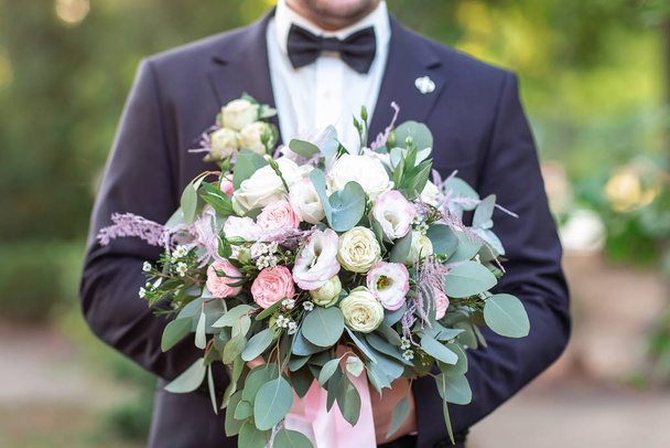 Svatební květiny v rukou ženicha. Mladý elegantní stylový muž oblečený v moderním formálním oblečení - Fotografie, Obrázek
