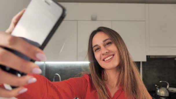 beautiful girl takes a selfie makes a selfie on a black phone on background of modern interior 4k - Video, Çekim