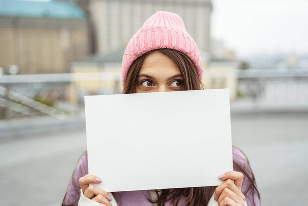 Emotional brunette girl covering her face with paper - Фото, зображення