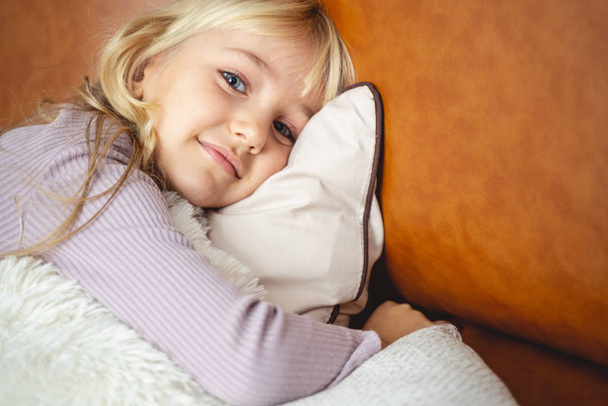 Adorable little girl lying on sofa at home - Foto, immagini