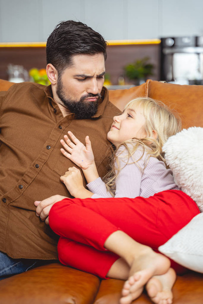 Cute little girl and her father sitting on couch - Foto, Imagen