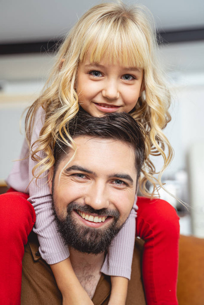 Adorable little girl sitting on shoulders of her dad - Photo, image