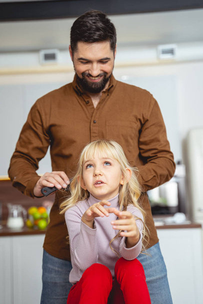 Cheerful father brushing hair of his daughter - Foto, immagini
