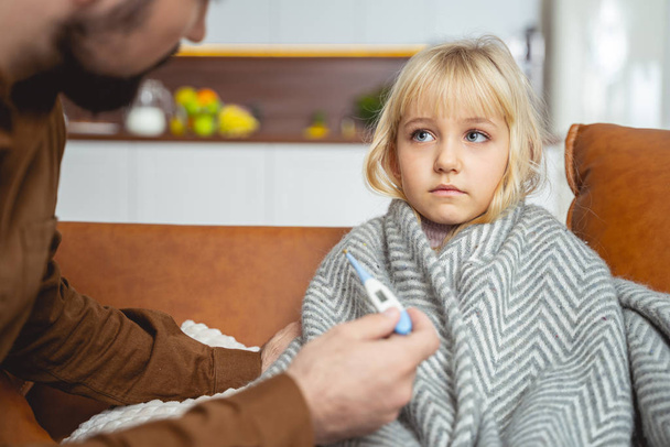 Caring father taking daughter temperature with thermometer - Photo, Image