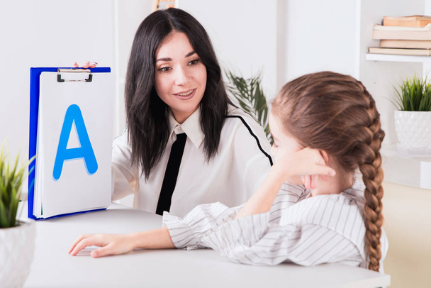 Child with therapist working on pronunciation and sounds together sitting in the class. - 写真・画像