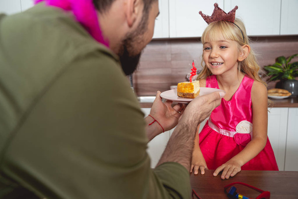 Father giving piece of cake to smiling daughter - Φωτογραφία, εικόνα