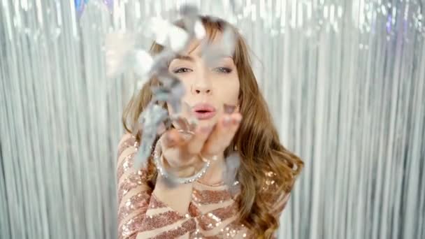 gyönyörű szexi fiatal nő fényes ruhában küld egy légcsók és pózol pezsgő üveg fényes ezüstös háttér - Felvétel, videó