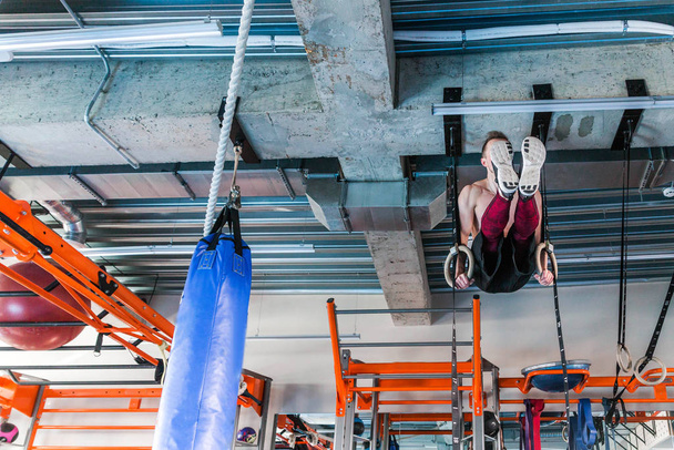 Фітнесмен висить на гімнастичних кільцях у спортивному залі
 - Фото, зображення