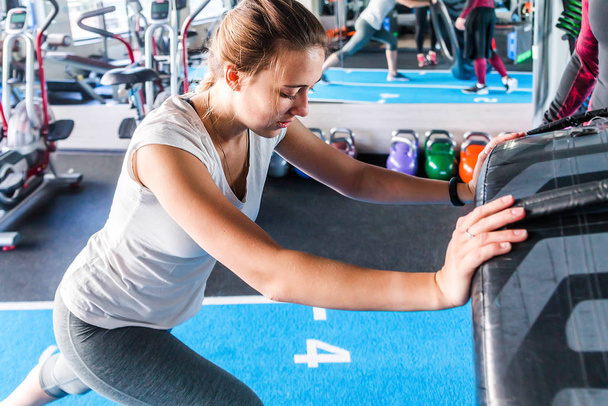 Ajuste atleta femenina haciendo ejercicio con un neumático enorme, girando y volteando en el gimnasio
.  - Foto, Imagen