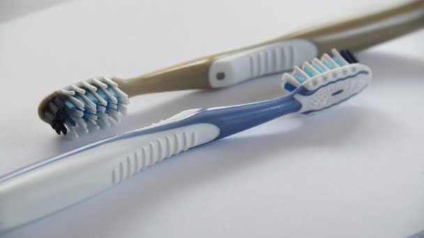 Két műanyag fogkefe forgó közelkép szürke háttér - Felvétel, videó