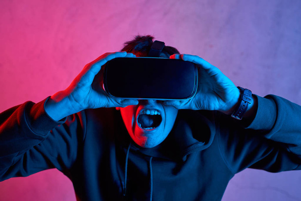 Junger Mann mit Virtual-Reality-Helm schreit in Kamera - Foto, Bild