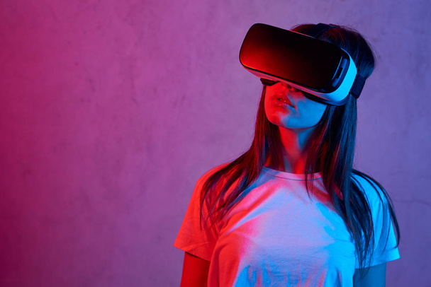 Young girl holding virtual reality helmet while wearing a white t-shirt - Valokuva, kuva