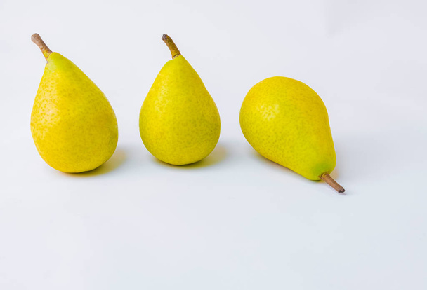 Bio pears lined up. Geometric composition of yellow pears on white background - Φωτογραφία, εικόνα
