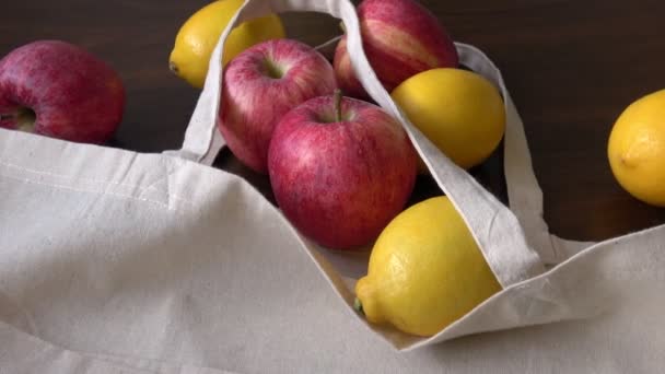 Eco τσάντα με φρούτα προϊόντα. Μηδέν απόβλητα χρησιμοποιούν λιγότερο πλαστικό έννοια. Φρέσκα φρούτα βιολογικά σε υφασμάτινες τσάντες eco cotton σε ξύλινο τραπέζι - Πλάνα, βίντεο