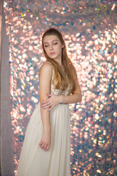 Retrato de beleza de uma menina bonita com um vestido de prata brilhante com maquiagem à noite em um fundo de luzes de Natal. - Foto, Imagem