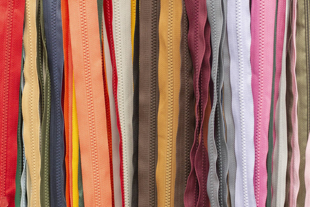 Background texture of zippers. a lot of zippers in different colors. vertical lines. sewing clothes, atelier, fabric and accessories shop. - Фото, изображение