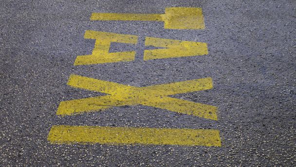 Asfalttaki sarı kelime Taksi. Caddenin zemininde taksi işareti var. Şehir caddesinde taksi durağı sarı sembollü harfler var.. - Fotoğraf, Görsel