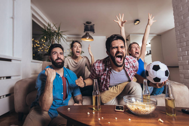 Gruppe gut gelaunter Freunde schaut Fußballspiel und feiert  - Foto, Bild