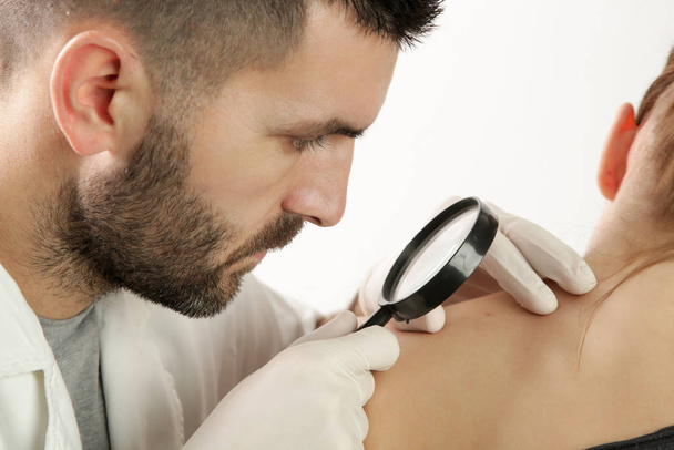 Dermatologista verificando toupeira através de lupa
 - Foto, Imagem