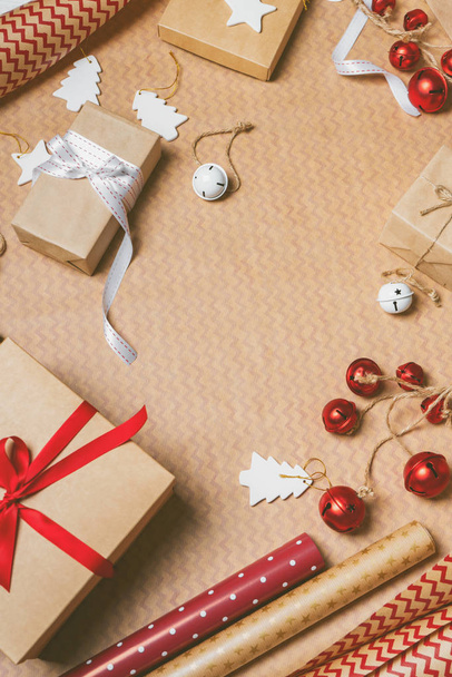 包装紙にギフトボックス、梱包テープ、ロープ、紙のロールや装飾小道具とクリスマスの背景。コピースペース付きのフラットレイアウト。クリスマスのお祝いの精神. - 写真・画像