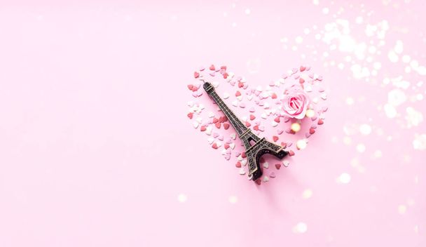 Valentines Day. Heart shape formed of sweet confetti on pink background with rose flower. Template mock up of greeting card or text design - 写真・画像