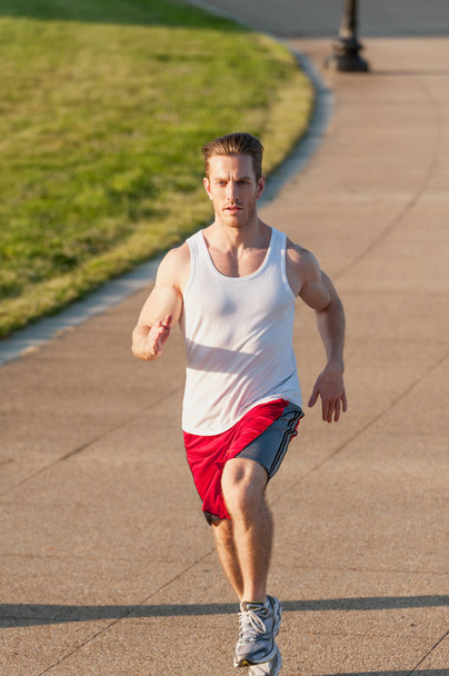 Caucasian man jogging outdoors in the early morning - Photo, Image