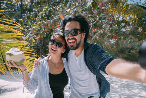 Пара влюбленных делают селфи под пальмой на тропическом пляже
 - Фото, изображение