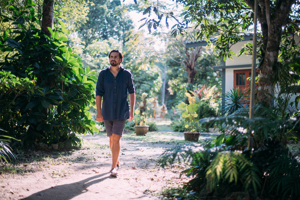 Egy fiatalember sétál a trópusi kertben..  - Fotó, kép