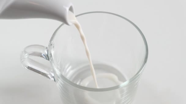 Pouring milk in the glass on white kitchen table. Close up. - Video
