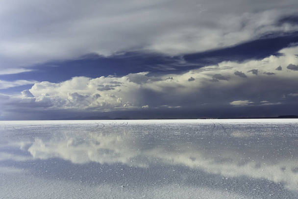 Viharos ég és a felhők tükröződése a sekély vízben. Fő hangsúly a felhők. Salar de Uyuni - Altiplano, Bolívia, Dél-Amerika. Fénykép nem zaj vagy lencse por. Ez egy darab só előtér.. - Fotó, kép