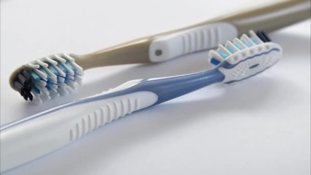 Dos cepillos de dientes de plástico girando de cerca sobre fondo gris
 - Imágenes, Vídeo