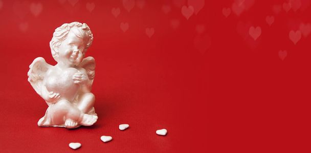 Sádrová figurka anděla se srdcem na červeném pozadí - Fotografie, Obrázek