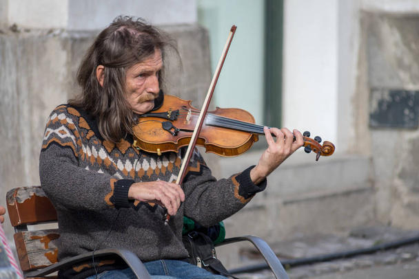 Timisoara, Rumunia - 17 listopada 2019: Człowiek grający na skrzypcach na ulicy. Prawdziwi ludzie.. - Zdjęcie, obraz