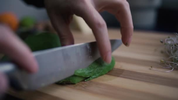 Close-up van vrouwelijke handen snijden een avocado met finesse - Video
