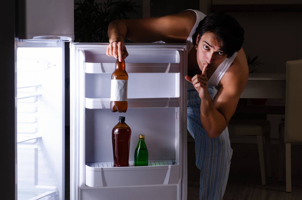Man breaking diet at night near fridge - Foto, afbeelding